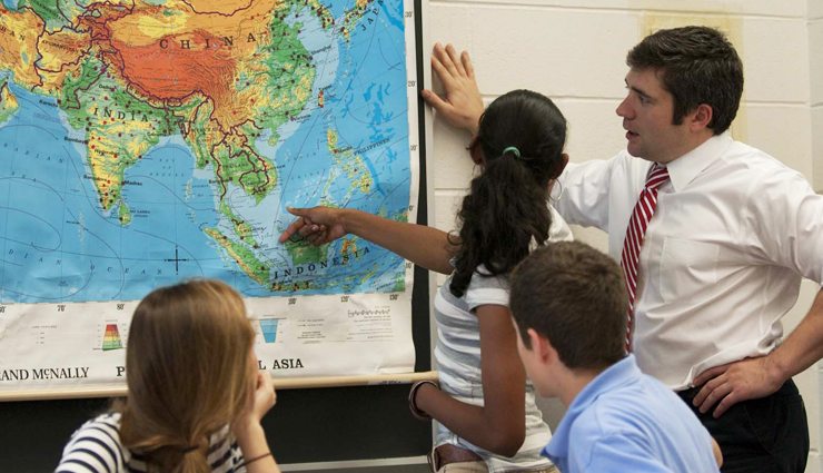 male teacher and group of students discuss map of Southeast Asia