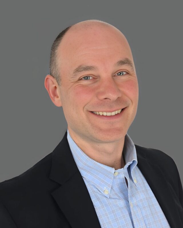 Smiling man in a suit with a gray background