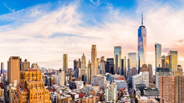 Skyline of a city with tall skyscrapers and a colorful sky, featuring a prominent tower on the right side of the image.