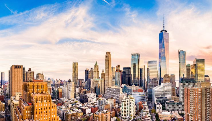 Skyline of a city with tall skyscrapers and a colorful sky, featuring a prominent tower on the right side of the image.