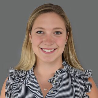 Smiling person wearing a striped blouse against a gray background.