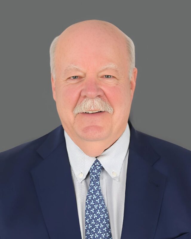 Man in a suit and tie with a gray background.