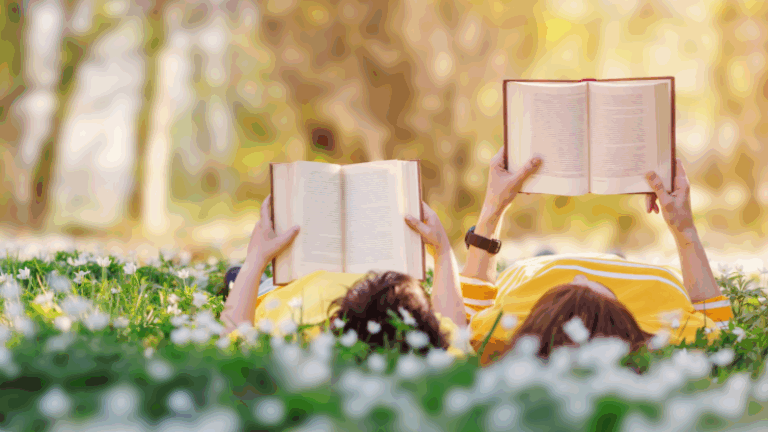 Two people lying on grass in a sunny field reading books surrounded by white flowers.