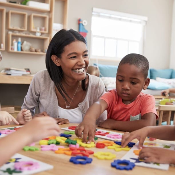 Teacher and children engaging in a colorful arts and crafts activity at a classroom table