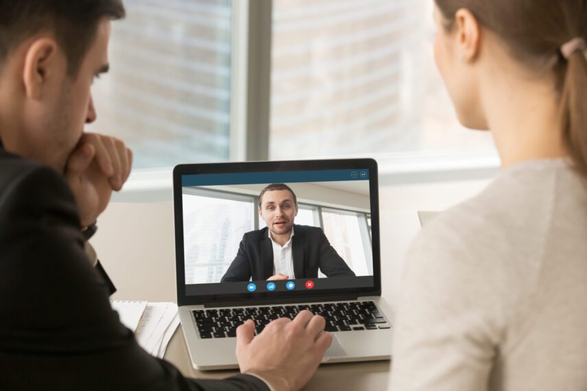 People having a video call on a laptop in a modern office setting