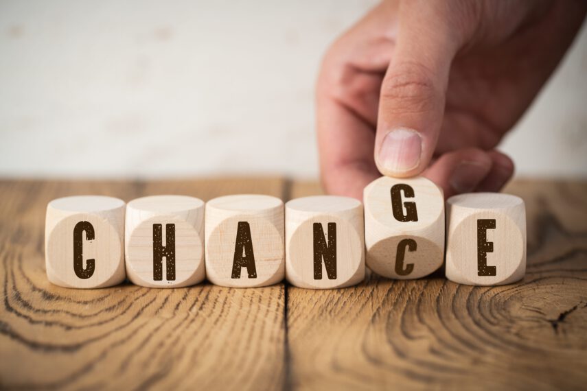 Hand flips one of six cubes with letters, turning the word "change" to "chance"