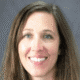 Smiling woman with long brown hair against a gray background