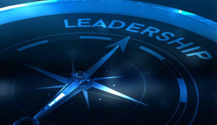 Compass pointing towards the word leadership, symbolizing direction and guidance in a blue-toned environment.