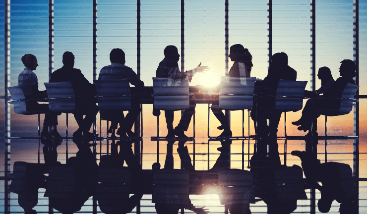 People having a meeting in an office with sunset in the background.