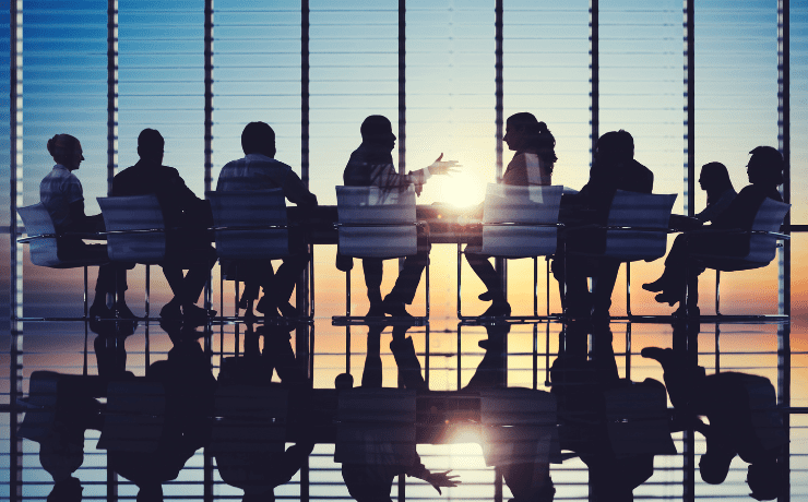 People having a meeting in an office with sunset in the background.