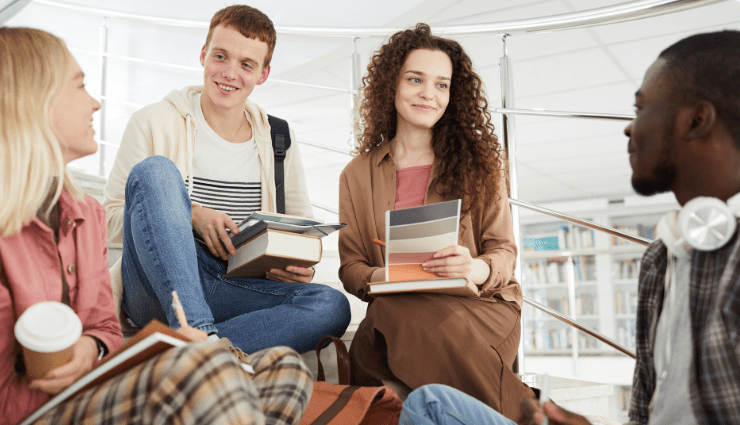 students sitting together on stairs with books and backpacks