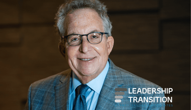 Smiling man wearing glasses and a plaid suit with the text "Leadership Transformation" in the corner