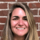 Woman smiling in front of a brick wall.