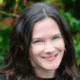 Smiling person with dark hair in a garden setting.