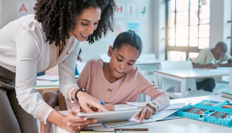 Teacher assists a student with classwork in a bright classroom setting.