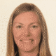 Woman smiling at the camera with light brown hair against a plain background.
