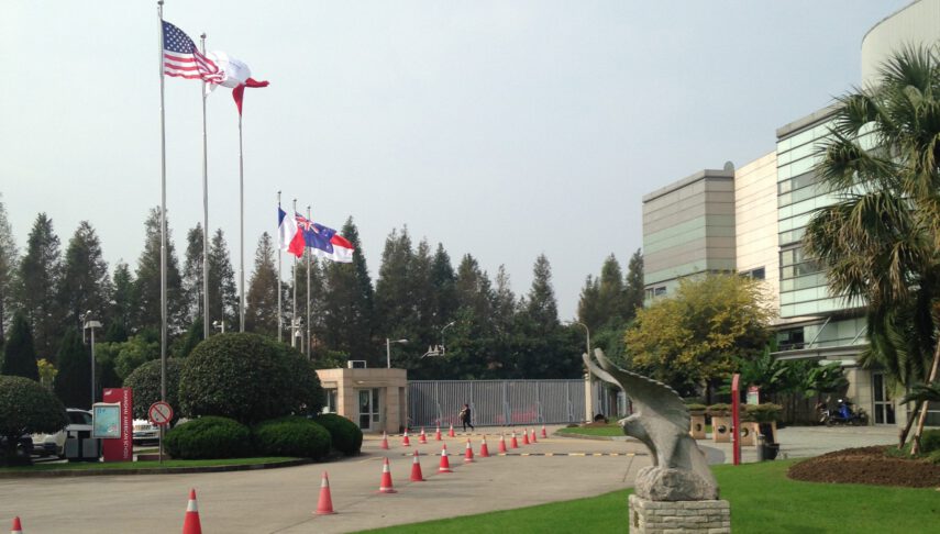 Driveway entrance to school with flags flying and orange cones in road