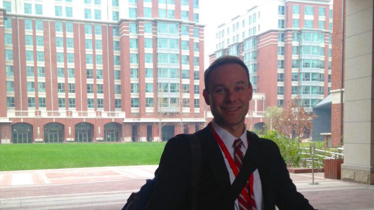 happy man in suit outside red building