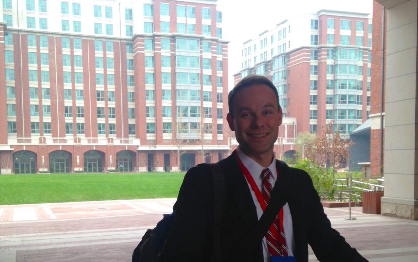 happy man in suit outside red building