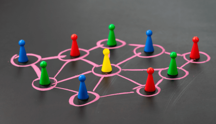 Colorful game pieces arranged on a chalk-drawn network diagram on a blackboard surface.