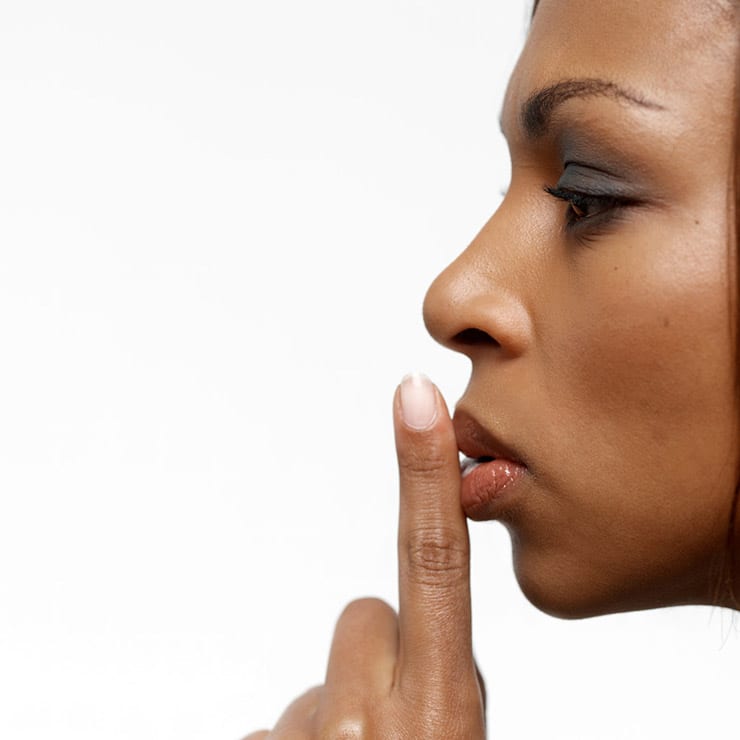 profile of woman holding finger to mouth to hush