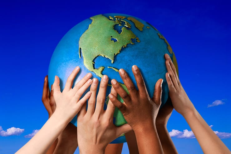 children's arms and hands of varying shades hold a globe