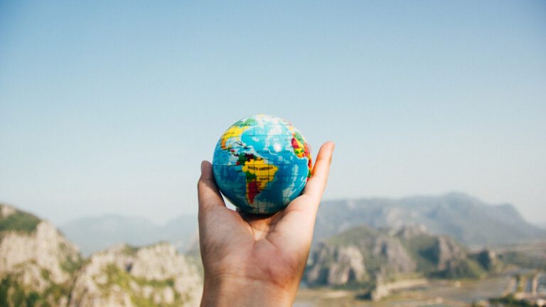 Outstretched hand holding a globe with mountains in background