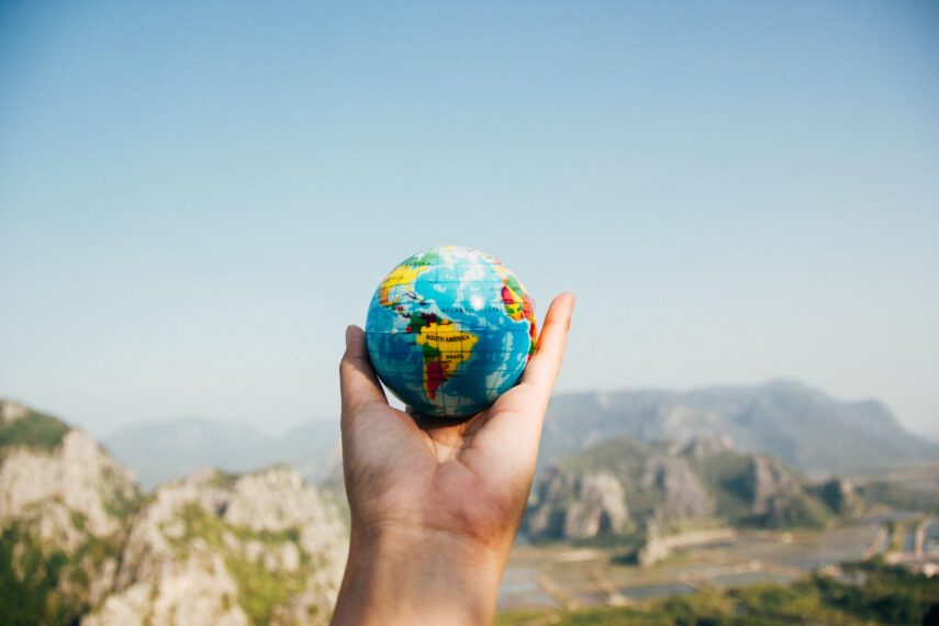Outstretched hand holding a globe with mountains in background