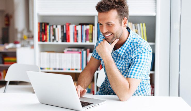 Man in gingham shirt smiling at laptop