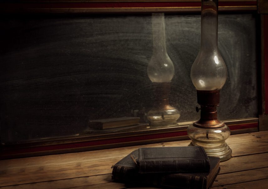 Old vintage mirror, oil lamp with old books on wooden table