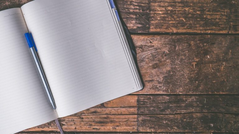 Open notebook sitting on a wood table.