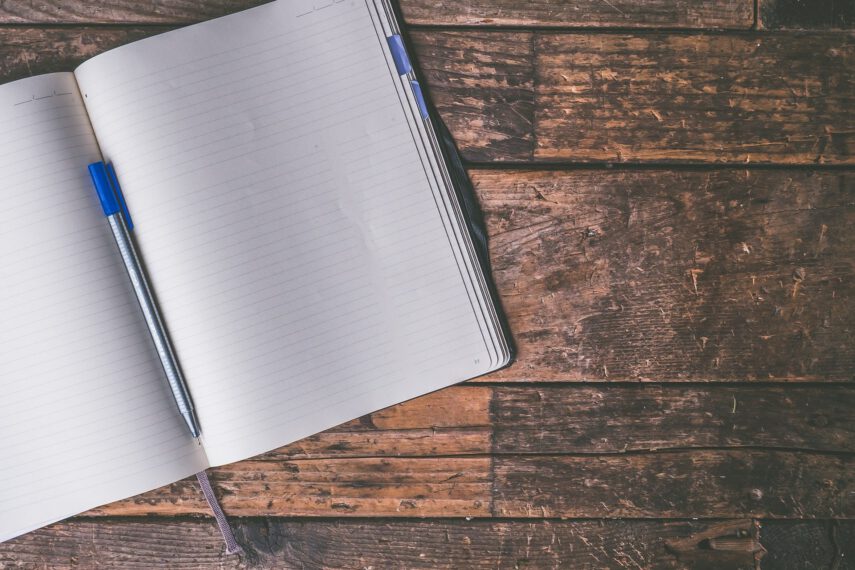Open notebook sitting on a wood table.