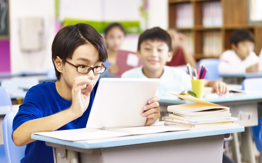 elementary schoolboy looking with curiosity at a tablet computer