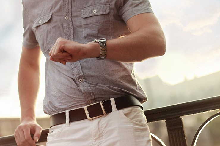 cropped image of man's torso and he checks wristwatch