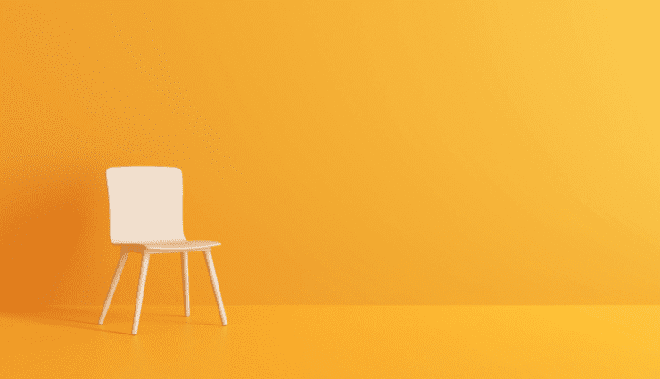 White chair against a bright orange wall with a geometric patterned floor in a minimalistic and modern setting.