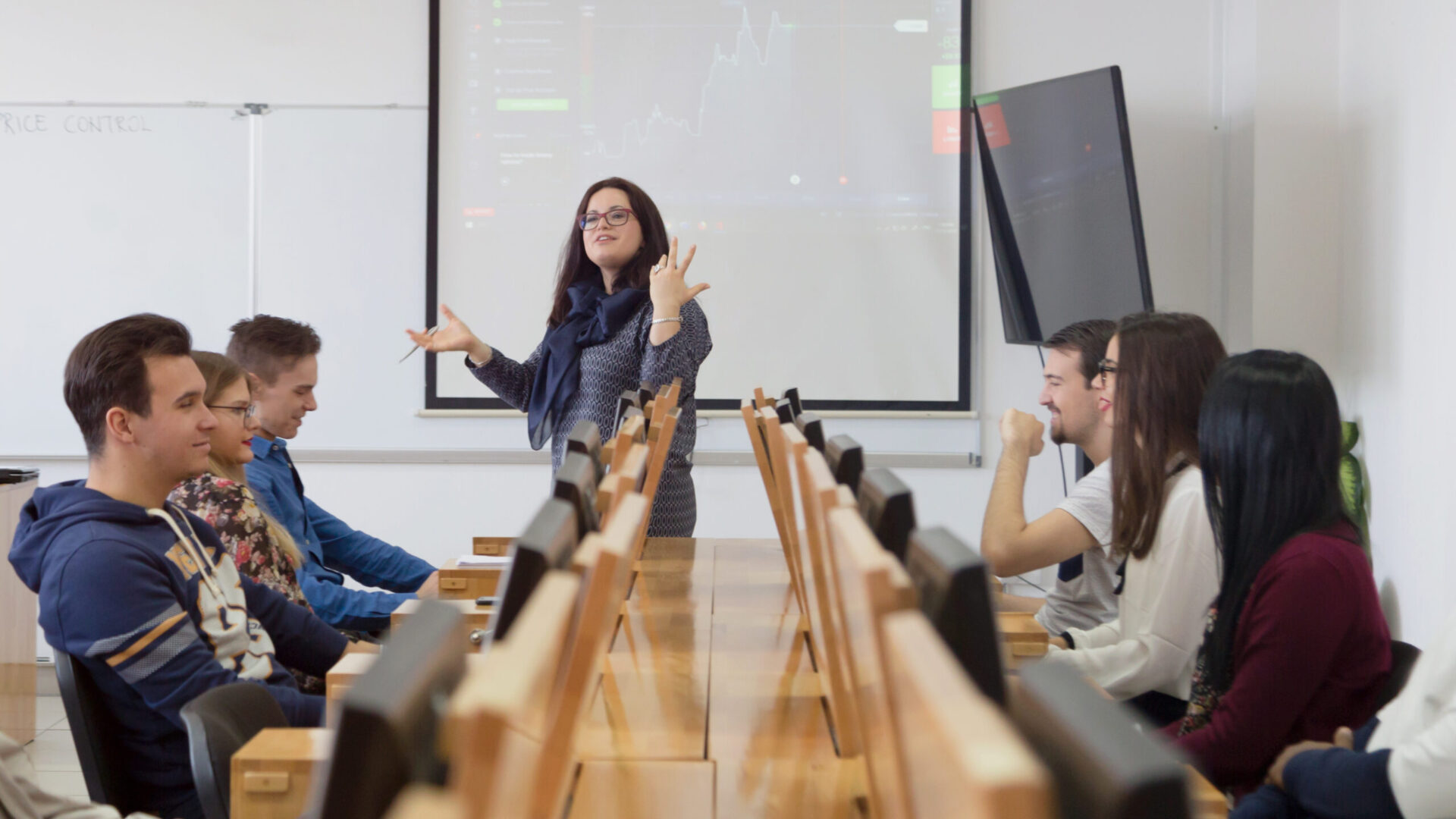 Female professor explain lesson to students and interact with them in the classroom.Helping a students during class. University student being helped by female lecturer during class.