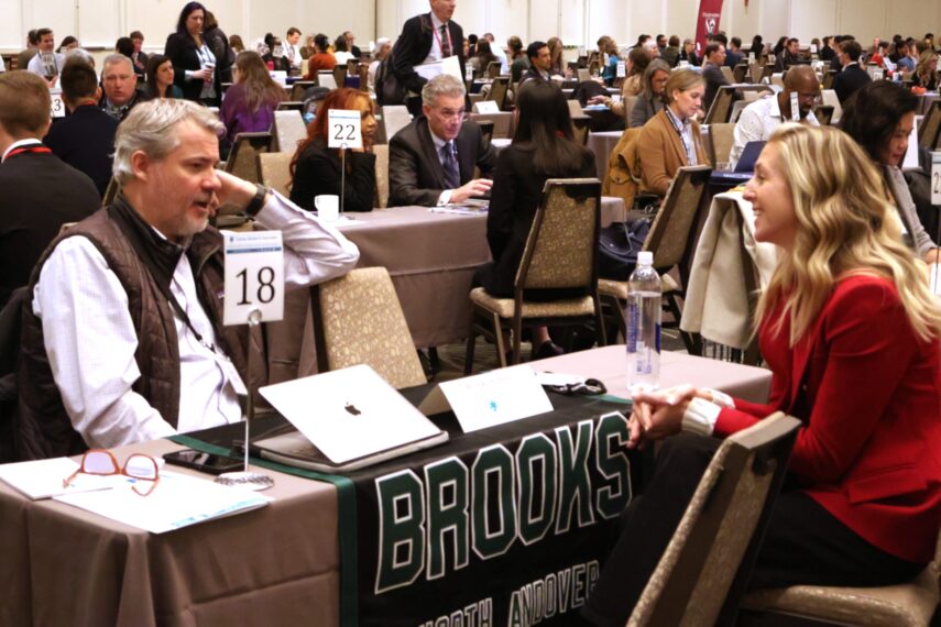People seated at tables in a conference setting, engaging in discussions and networking activities.