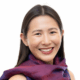 A person smiling, wearing a colorful scarf, with a neutral background.