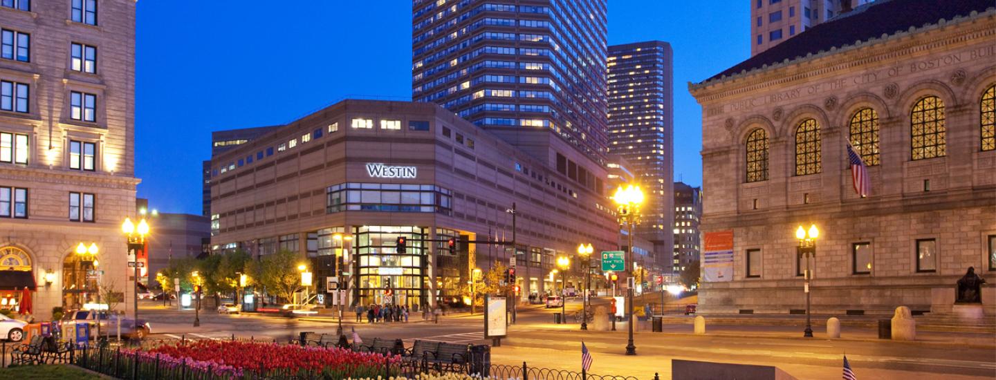 Cityscape at dusk with illuminated buildings and the Westin Hotel, surrounded by street lamps and urban scenery.