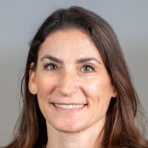 Smiling person with long dark hair against a neutral background.