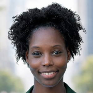 Smiling person with curly hair standing outdoors in an urban setting.